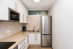 A compact kitchen with white cabinets, a stainless steel refrigerator, a microwave, and a coffee maker. - GuestReady - Alemania Villa Garden (San Bartolomé de Tirajana)