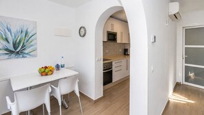 A modern kitchen with white cabinetry, a microwave, and a coffee maker. - GuestReady - Alemania Villa Garden (San Bartolomé de Tirajana)