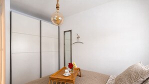 A bedroom with a bed, a small wooden table with a vase of flowers, a hanging light fixture, and a mirror on the wall. - GuestReady - Casa Dey with terrace (Telde)
