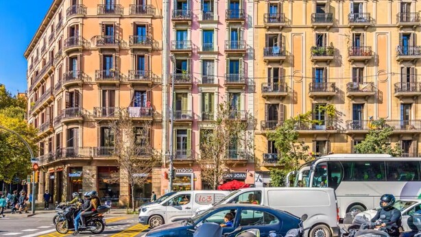 Un edificio de varios pisos con balcones, una farmacia y una parada de autobús.