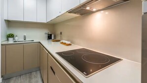 Una cocina moderna con armarios blancos, una campana extractora de acero inoxidable y una placa de inducción negra.