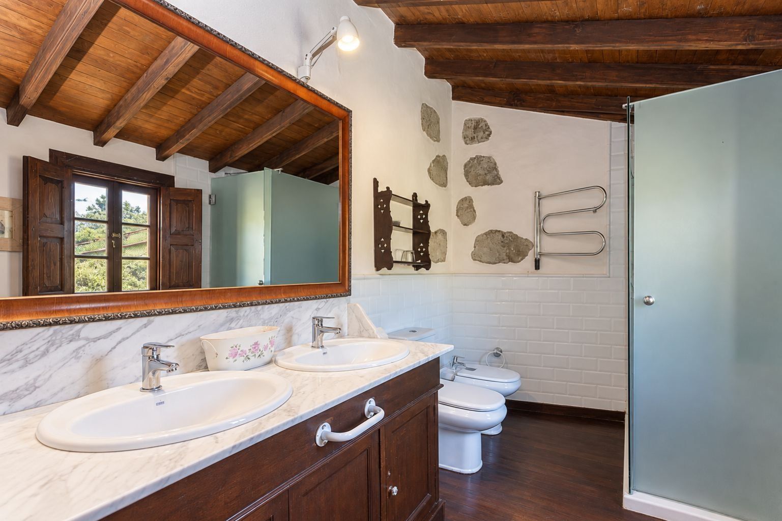 A bathroom with two sinks, a toilet, a mirror, and a shower.