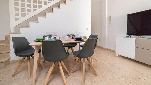 Ein Essbereich mit Treppe, Fernseher und weißem Schrank.
