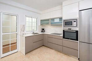 A modern kitchen with a stainless steel refrigerator, built-in microwave, oven, and a coffee maker on the countertop. - GuestReady - Puerto Rico Family Retreat (Las Palmas de Gran Canaria)