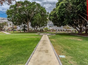 A pathway leading through a park with trees and a building in the background. - GuestReady - Puerto Rico Family Retreat (Las Palmas de Gran Canaria)