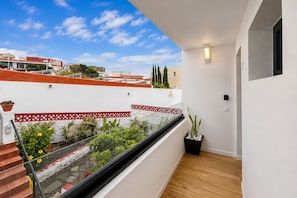 Ein Balkon mit Blick auf Gebäude, Holzboden und einem Blumentopf.