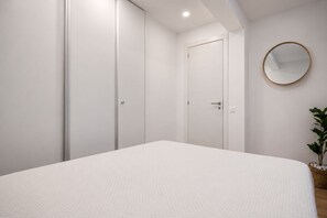 A bedroom with a bed, a wardrobe, a door, and a round mirror on the wall. - GuestReady - Bunker Luxury with Ocean View (Playa del Hombre)