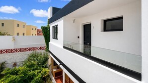 A modern two-story building with a balcony, a black door, and a small window.