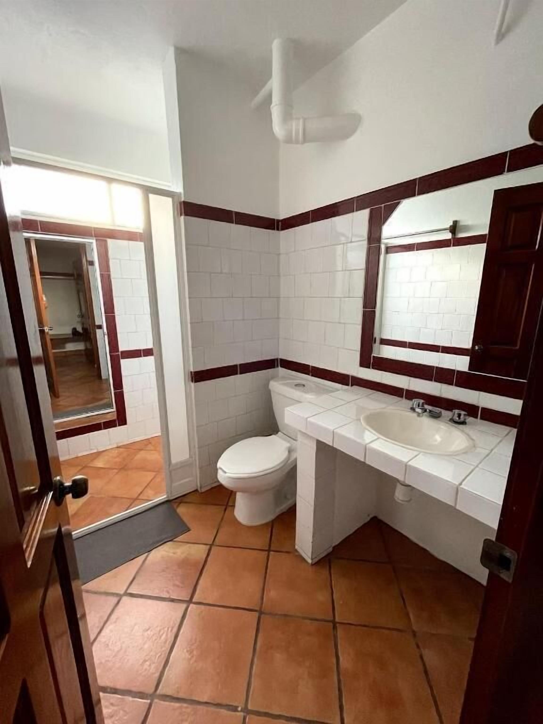 A bathroom with a toilet, sink, and mirror.