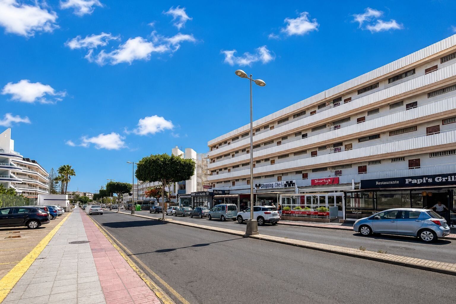 A multi-story hotel with a flat facade, a restaurant named 'Papi's Grill,' and a shopping center.