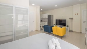 A modern hotel room with a bed, a desk, a TV, and a kitchenette. - GuestReady - 01A Livian Suites 1A Int 2pax (Las Palmas de Gran Canaria)