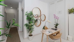 A modern room with a desk, chairs, a potted plant, and wall-mounted mirrors. - GuestReady - 01A Livian Suites 1A Int 2pax (Las Palmas de Gran Canaria)