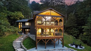 A two-story wooden cabin with a balcony, stone steps, and a stone foundation. - Walk to Beech Slopes | Hot Tub, Sleeps 8 (Beech Mountain)
