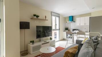 A modern living room with a sofa, TV, and a small white table.