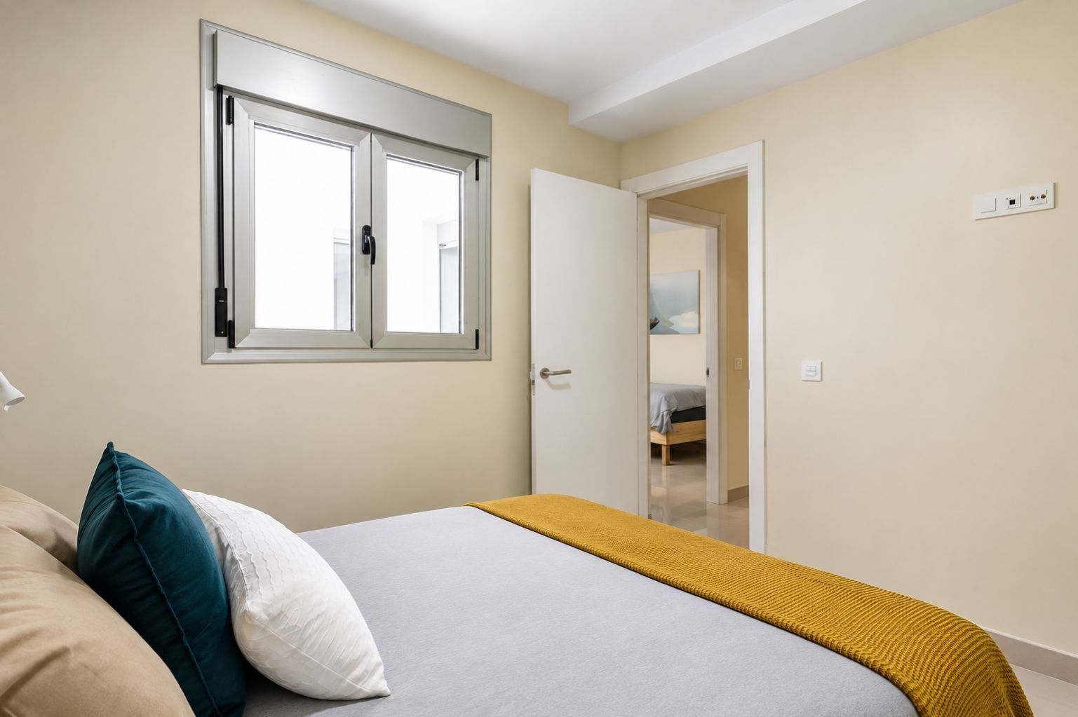 Una camera da letto con un letto, una finestra, una porta e una lampada da comodino.