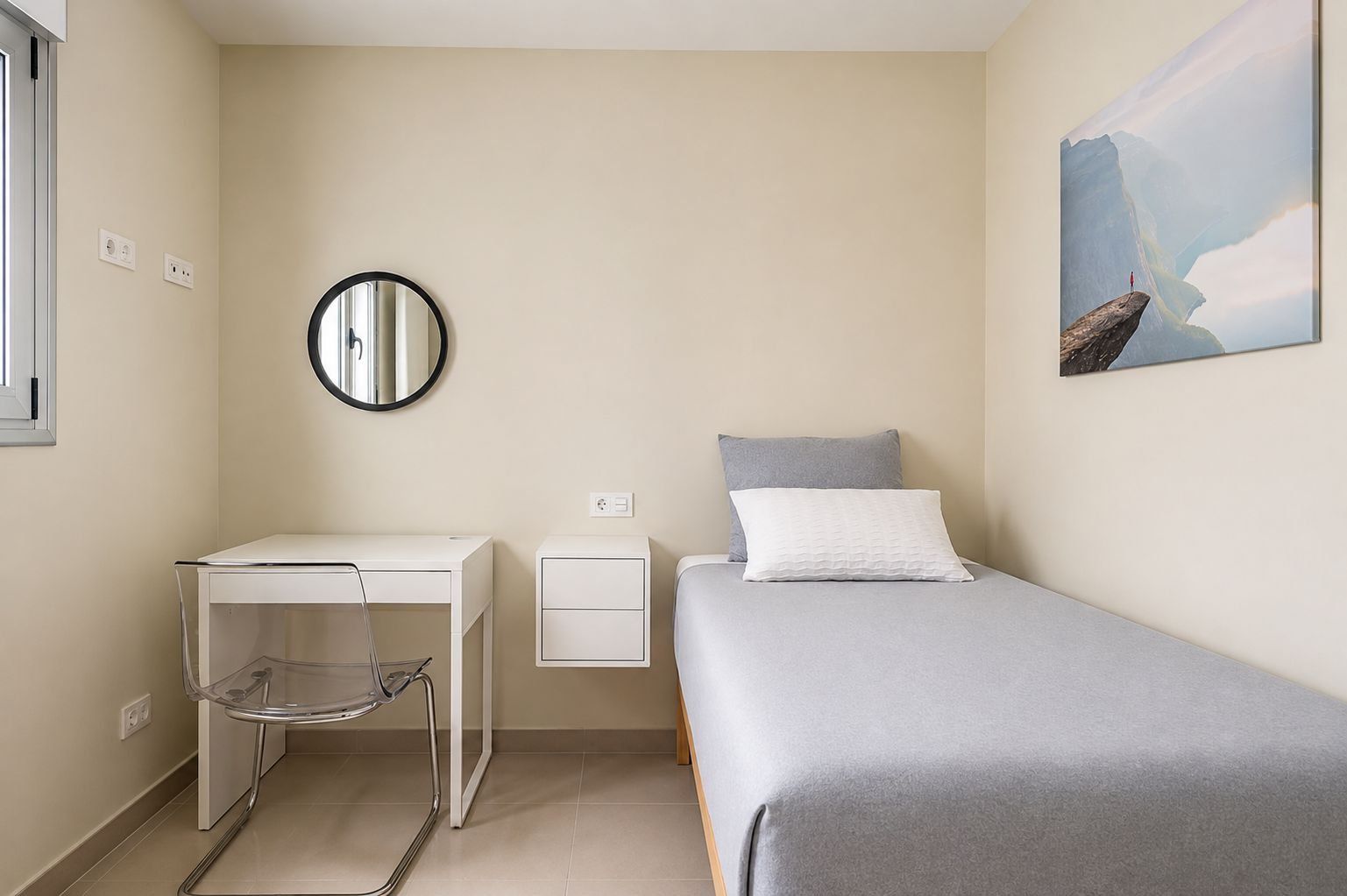 Ein Schlafzimmer mit einem Bett, einem Schreibtisch, einem Sessel, einem Nachttisch und einem wandmontierten Spiegel.
