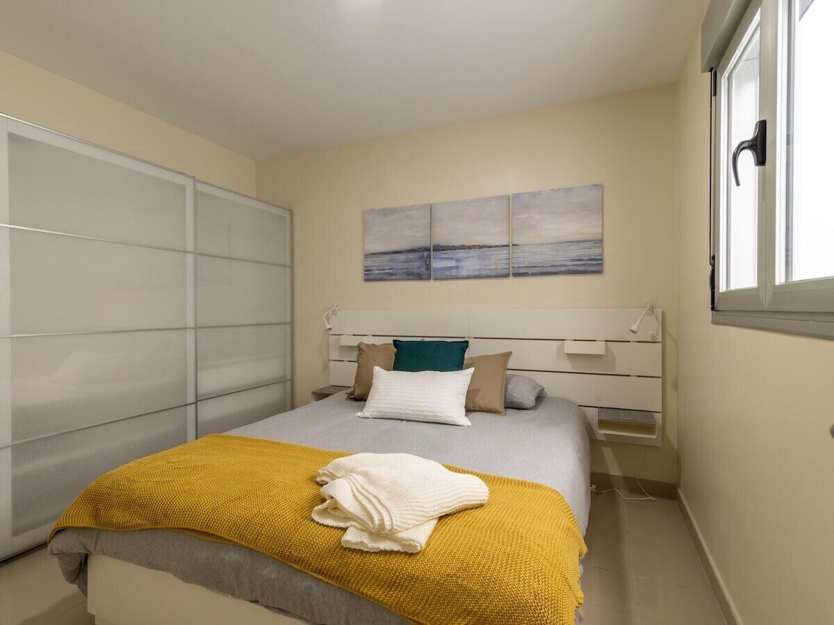 A bedroom with a bed, a bedside table, a wardrobe, and a window.