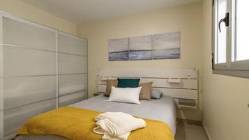 A bedroom with a bed, a bedside table, a wardrobe, and a window.