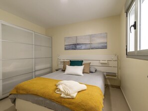 A bedroom with a bed, a bedside table, a wardrobe, and a window. - GuestReady - 02B Livian Suites Int 4 Pax (Las Palmas de Gran Canaria)