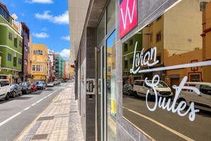A street view with a building featuring a prominent 'W' sign and the name 'Lilian Suites' in cursive. - GuestReady - 03C Livian Suites Ext 4 Pax (Las Palmas de Gran Canaria)