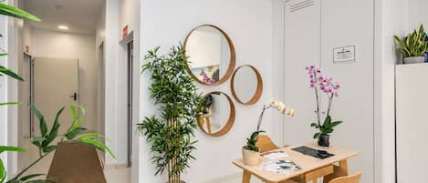 A modern office space with a desk, chairs, a potted plant, a mirror, and a door.
