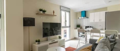 A modern living room with a sofa, TV, and a small white table.