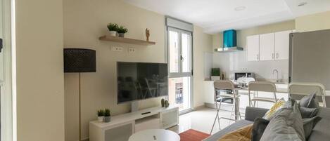 A modern living room with a sofa, TV, and a small white table.