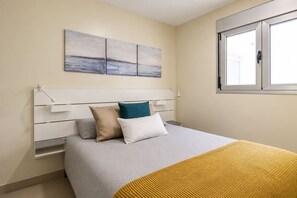 Ein Schlafzimmer mit Bett, Kopfstütze, Fenster und einem Wandbild.