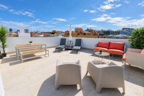 Terraço no telhado com área de estar ao ar livre, incluindo um banco, cadeiras de descanso e um sofá.
