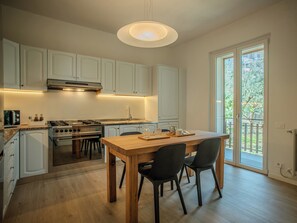 Une cuisine moderne avec des meubles blancs, une table à manger en bois et des chaises.