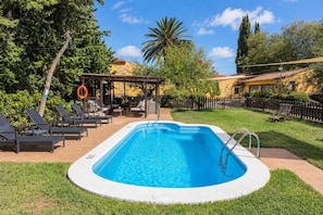 A rectangular swimming pool with a lifebuoy, lounge chairs, and a covered seating area. - GuestReady - Las Calas 4 Double Room Lirio (Vega de San Mateo)