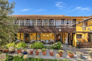 A two-story building with a tiled roof, outdoor seating area, and potted plants. - GuestReady - Las Calas 4 Double Room Lirio (Vega de San Mateo)