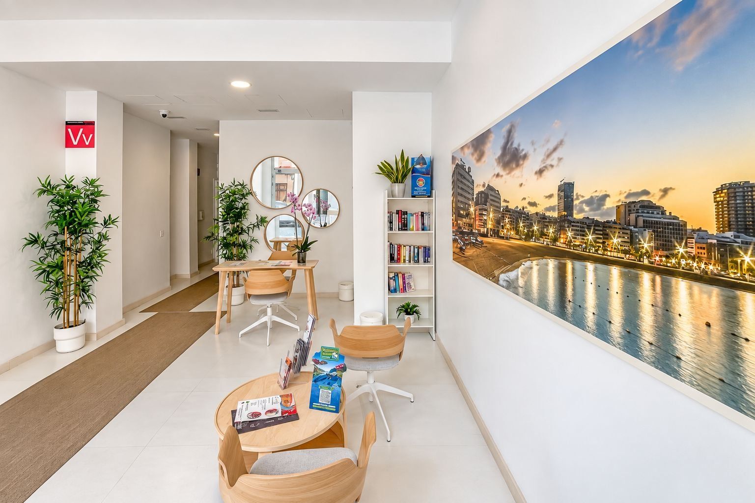 Une chambre d’hôtel moderne avec vue sur la ville, un coin repas avec une table et des chaises, et une bibliothèque remplie de livres.