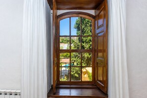 Un couloir avec une grande fenêtre en arc de cercle, des rideaux blancs et un radiateur.