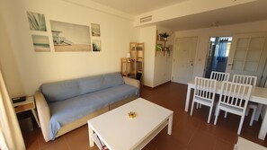 Un salon comprenant un canapé, une table basse et un coin repas avec des chaises et une table.