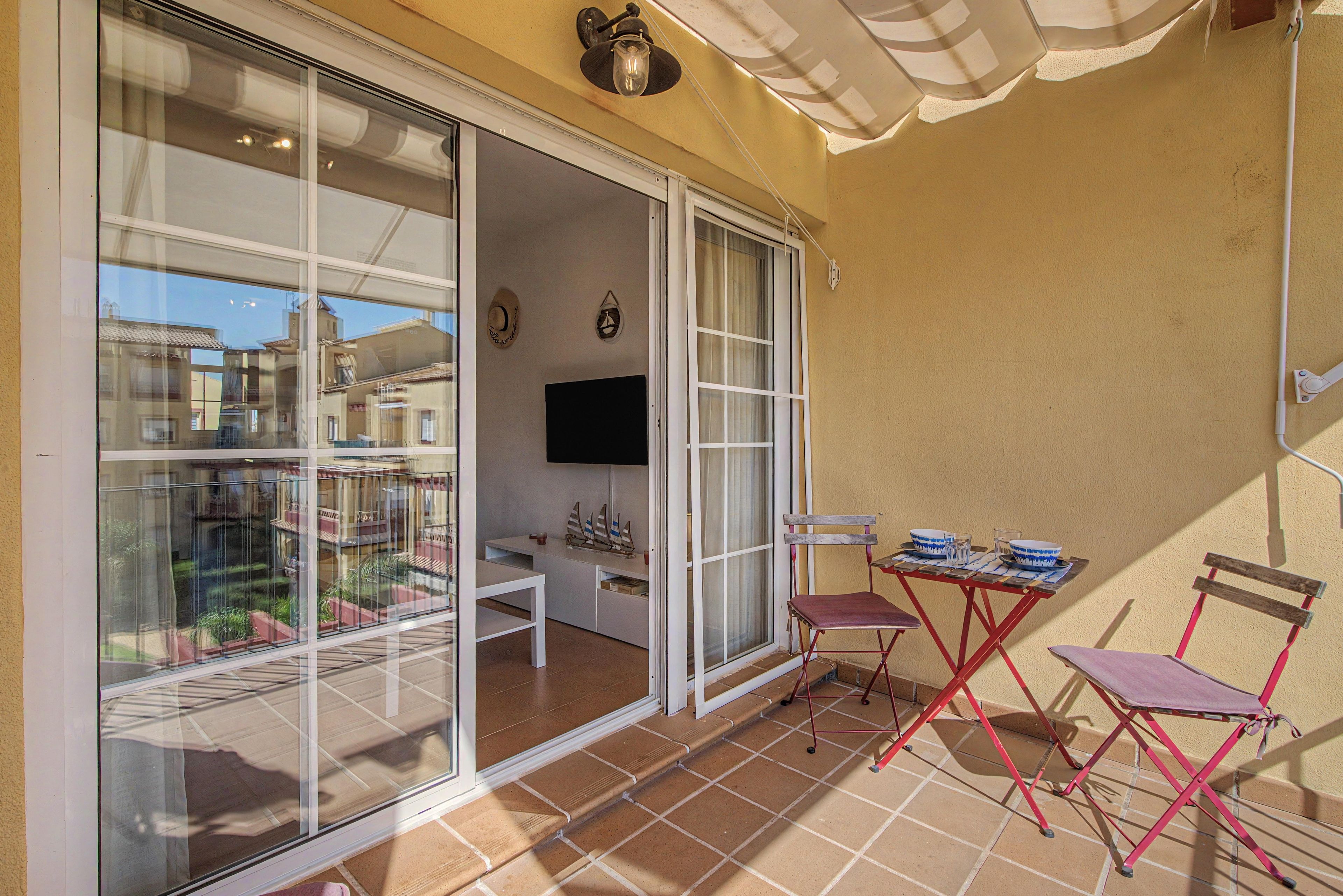 A balcony with a table, chairs, and a TV.