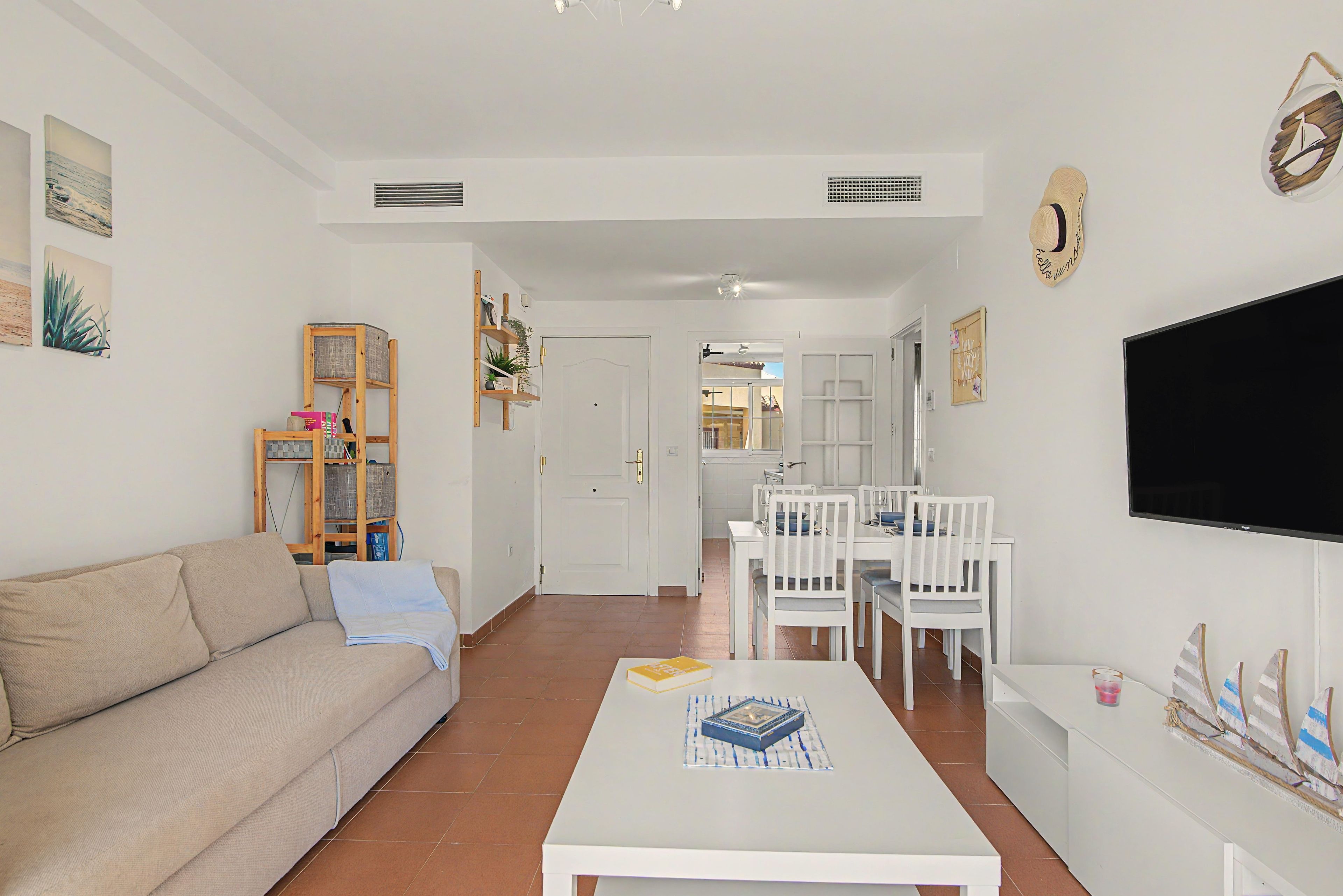 A living room with a sofa, a coffee table, and a dining area with chairs and a table.