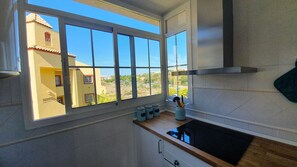 Une cuisine avec une grande fenêtre, une cuisinière et un évier.