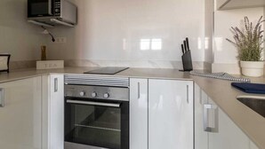 Une cuisine moderne équipée d’un four encastré, d’un four à micro-ondes et d’une cuisinière à gaz.