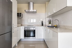 A modern kitchen with stainless steel appliances, white cabinetry, and a marble countertop. - GuestReady - 05A Livian Suites Int 3 Pax (Las Palmas de Gran Canaria)