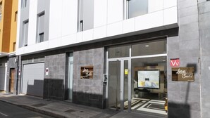 L’entrée d’un hôtel, avec une porte en verre, une enseigne et un intérieur visible à travers le verre.