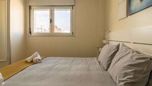 Une chambre d’hôtel avec un lit, une fenêtre, un tableau et une serviette sur le lit.