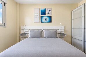 A bedroom with a bed, two bedside tables, and wall art depicting ocean scenes. - GuestReady - 04A Livian Suites Int 3 Pax/Terraza (Las Palmas de Gran Canaria)