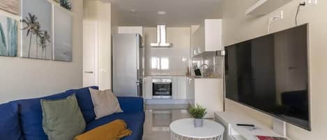 A modern living room with a blue sofa, a flat-screen TV, and a small round table.