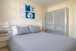 Ein modernes Hotelzimmer mit einem großen Bett, einem Kleiderschrank und Wandbildern mit Meeresmotiven.