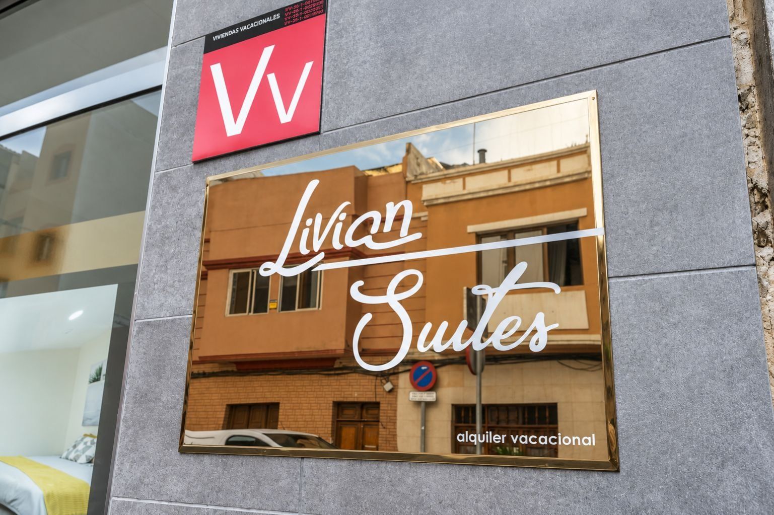 Segnaletica per Livia Suites, con il riflesso di un edificio e un'auto.