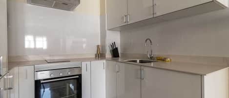 A modern kitchen with white cabinetry, a stainless steel oven, and a built-in sink.