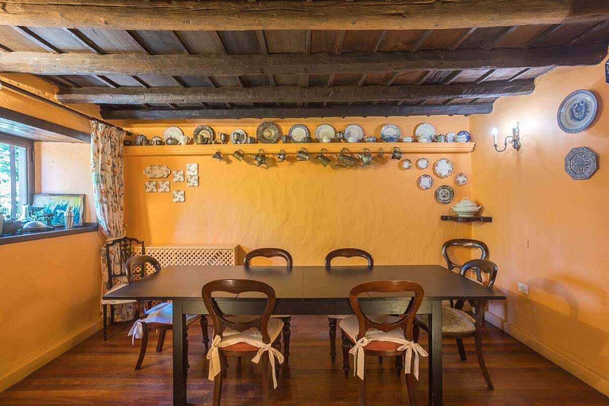 A dining room with a wooden table and chairs, a wall decorated with plates and a hanging garland.