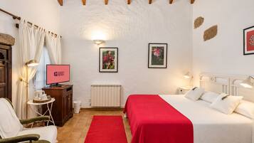 Een hotelkamer met een bed, bureau, stoel, televisie en radiator.