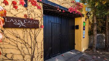 A hotel entrance with a black gate, a sign reading 'Las Calas Hotel', and a small sign indicating a handicap accessible entrance.
